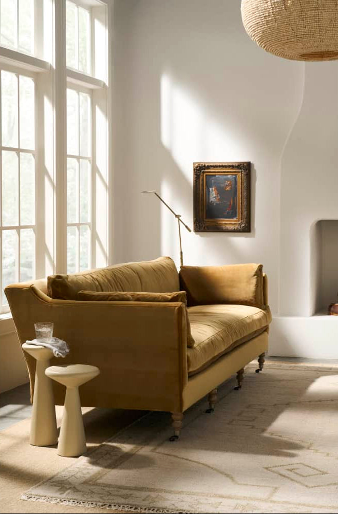Living room with mustard yellow sofa, side tables, and a framed picture on the wall.