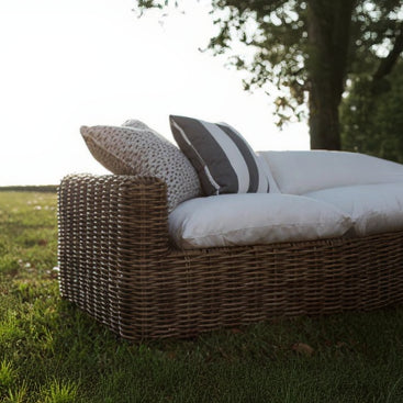 Wicker outdoor sofa with cushions on a grassy area