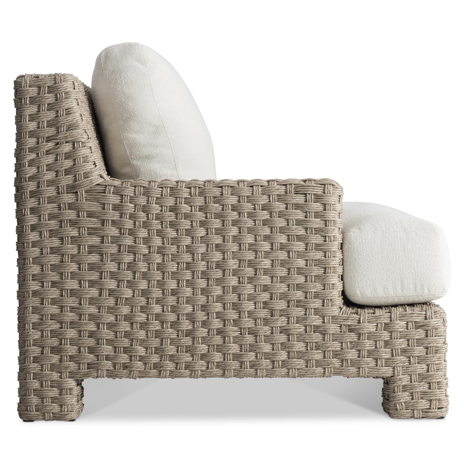 A side profile of the outdoor lounge chair, emphasizing the wide armrests, plush seat cushion, and the intricate handwoven wicker detailing.