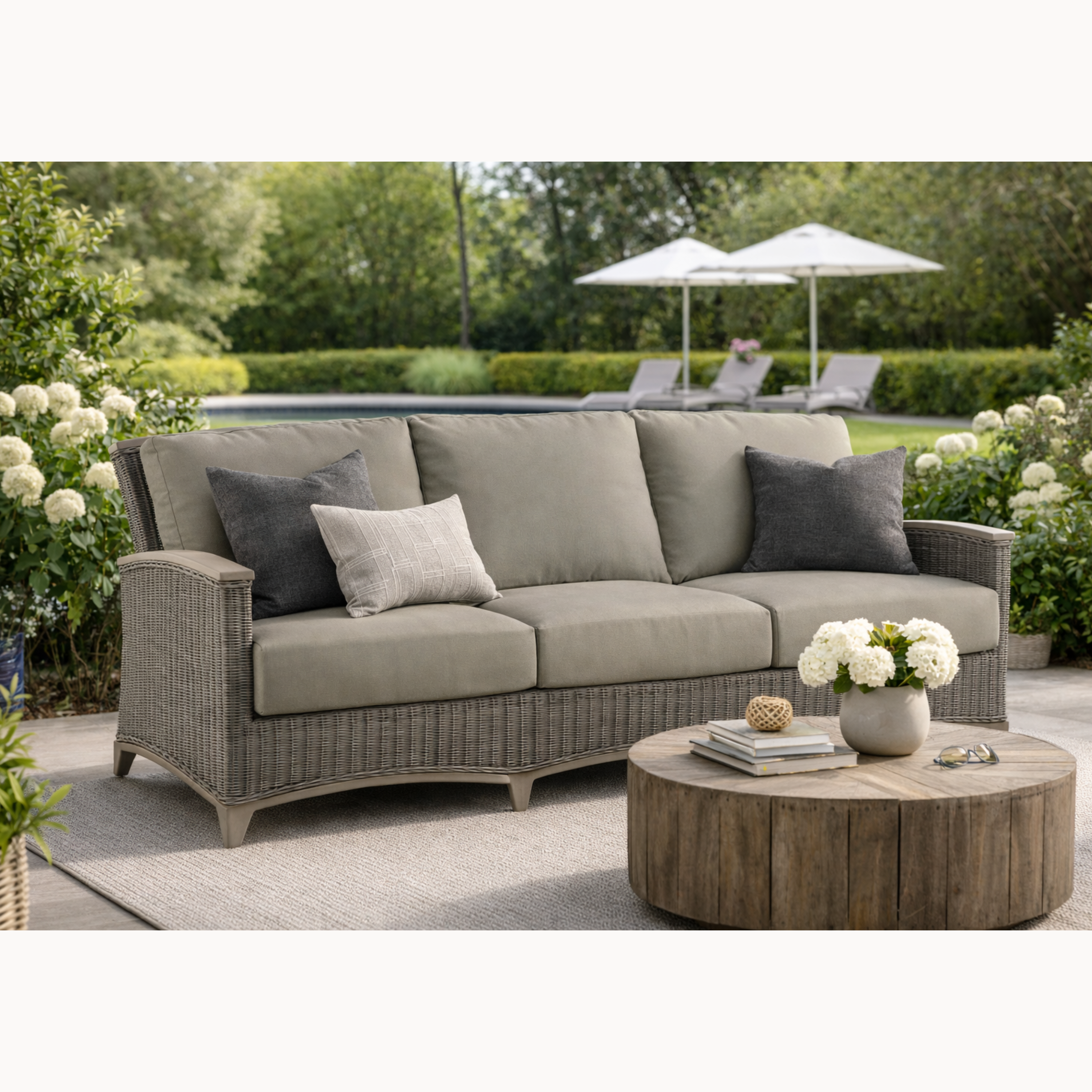 Outdoor patio set with a sofa, coffee table, and chairs in a garden setting.