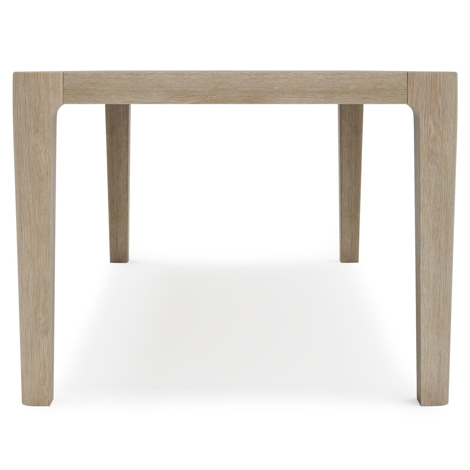 A modern outdoor dining table crafted from teak in a Sea Oat finish. The rectangular tabletop has softly rounded corners, while the tapered legs add a refined and polished look.