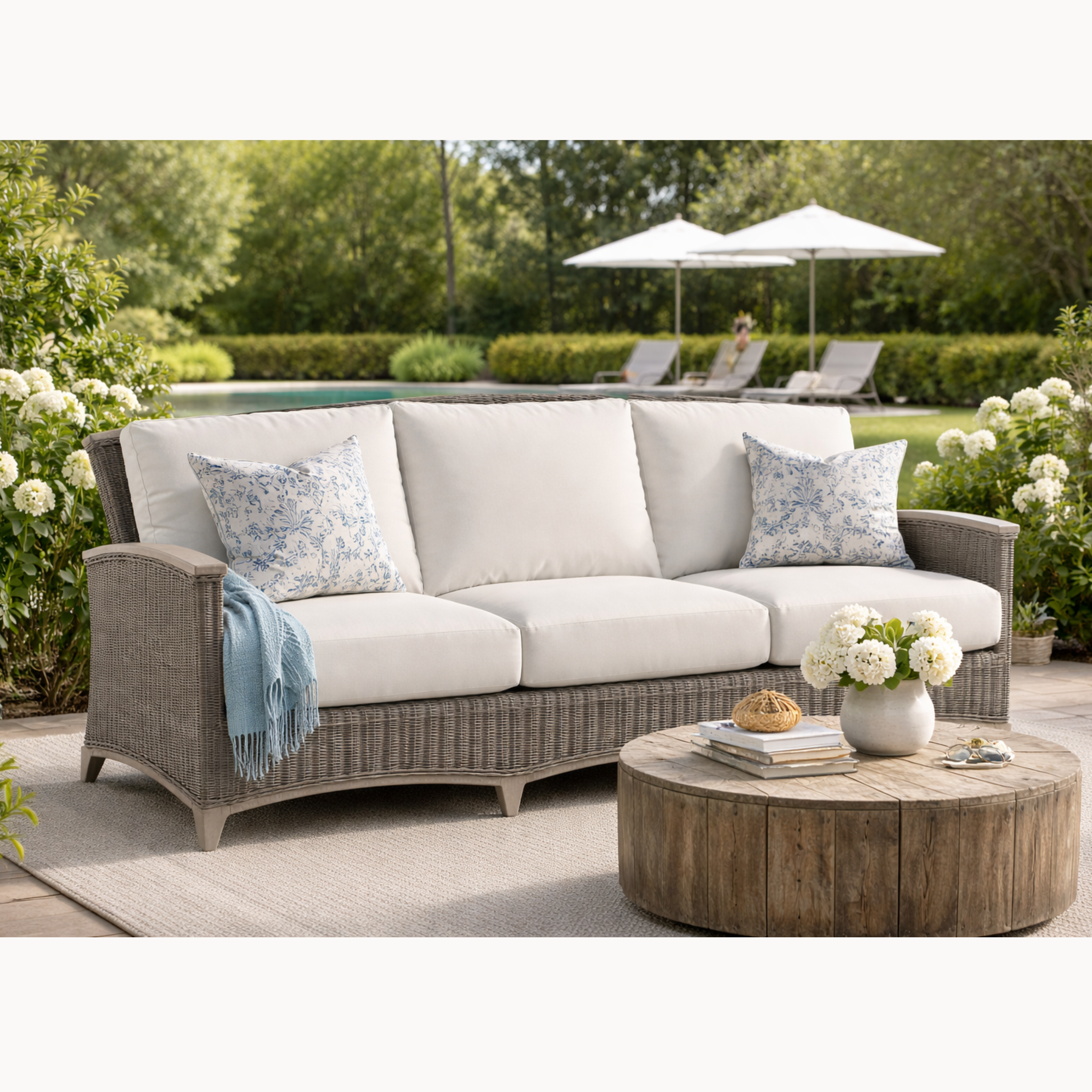 Outdoor patio set with sofa, coffee table, and decorative elements in a garden setting.