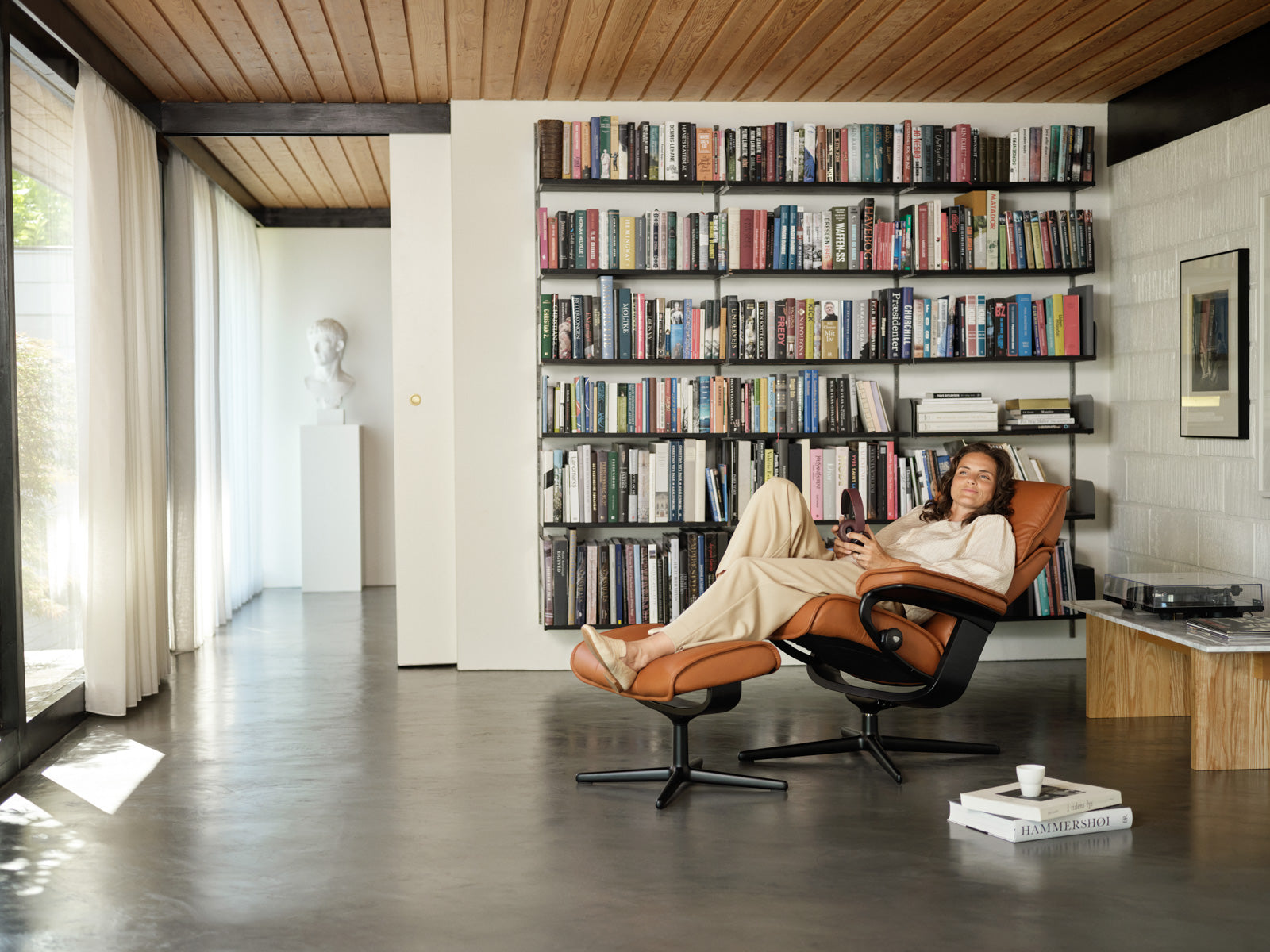 Woman reading in a Stressless Admiral recliner in a cozy home library